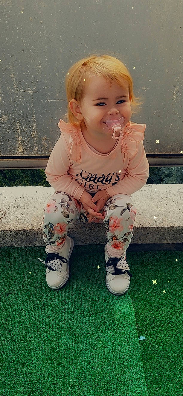 Valëntina participe au concours pour gagner de l'argent avec cette photo : baby, baby_toddler_clothing, blond, cheek, child, facial_expression, grass, hair, hairstyle, happy, head, joy, knee, pattern, person, pink, shoe, sitting, skin, sleeve