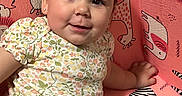 Amarosa is registered to the contest to win money with this photo: baby, child, smiling, sitting, floral_clothing, yellow_shorts, pink_background, animal_print, face, cute, happy, indoors, earrings, portrait, infant, bright_colors, young_child, playful, decor, person