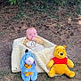 baby, blanket, plush_toy, winnie_the_pooh, eeyore, outdoor, grass, tree, shade, child, toy, nature, ground, person, cute, cozy, smiling, happy, sitting, forest_floor
