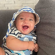 Noé participe au concours pour gagner de l'argent avec cette photo : baby, child, smiling, happy, hat, striped_clothing, couch, indoor, infant, cute, portrait, person, sitting, young_child, joyful, face, expression, casual, comfortable, relaxed