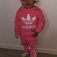 Elyanna participe au concours pour gagner de l'argent avec cette photo : toddler, child, pink_clothing, adidas, sweatshirt, pants, socks, standing, smiling, indoor, wooden_floor, wall, hair, face, person, casual, cute, fashion, young_child, portrait