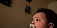 Kingston joined the competition — help win amazing prizes! toddler, pacifier, child, indoor, person, hand, face, couch, blanket, wall, decor, clothing, sitting, expression, young_child, holding, beaded_chain, profile, dark_room, relaxed