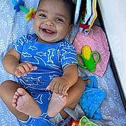 Ezekiel joined the competition — help win amazing prizes! baby, infant, smiling, blue_onesie, shark_pattern, toys, teether, blanket, playtime, happy, cute, child, feet, hand, indoor, colorful, soft_toys, face, portrait, lying_down