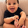baby, child, smiling, happy, sitting, foot, hand, couch, pillow, indoor, cute, person, infant, black_clothing, skin, expression, portrait, young, toes, playful
