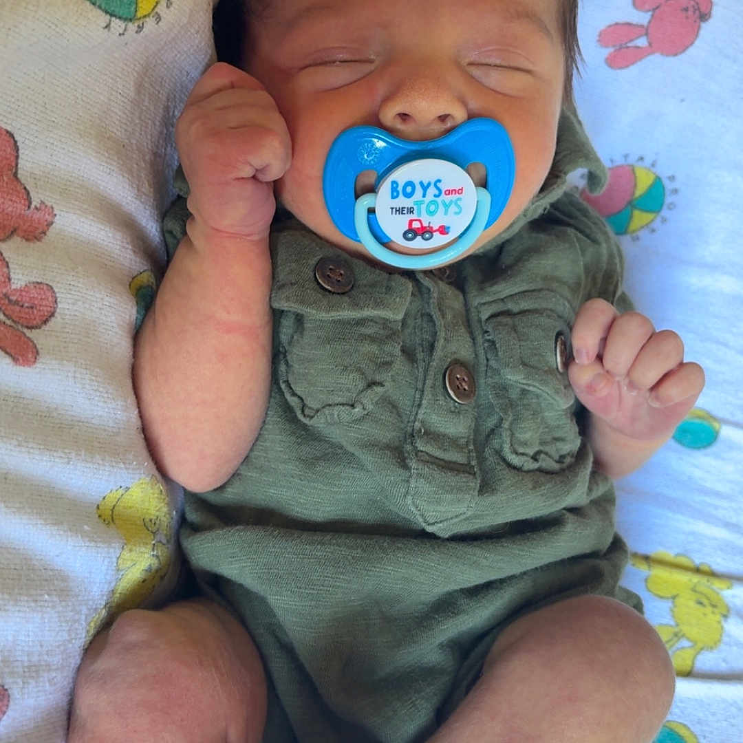 Westin is registered to the contest to win money with this photo: newborn, baby, pacifier, sleeping, infant, green_outfit, white_socks, blanket, patterned_blanket, peaceful, cute, resting, child, small_hands, small_legs, indoors, closeup, portrait, soft_lighting, cozy