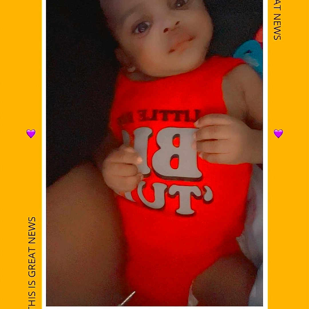 Demarcus joined the competition — help win amazing prizes! baby, baby_girl, child, closeup, cute, face, frame, hand, heart_emoji, indoors, infant, looking_up, person, portrait, red_clothing, skin, smile, text_overlay, yellow_background, young_child