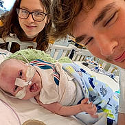 Raymond joined the competition — help win amazing prizes! baby, infant, hospital, medical_tube, blanket, adult, glasses, smile, bed, toy, healthcare, care, family, cozy, person, indoor, portrait, happy, lying_down, parent
