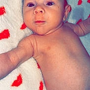 Andrew Mason is registered to the contest to win money with this photo: baby, infant, blanket, red_hearts, diaper, skin, face, arm, lying_down, cute, newborn, child, young, soft_texture, pattern, expression, closeup, indoors, comfort, portrait