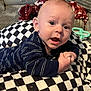 baby, infant, child, face, eyes, mouth, hand, pillow, checkered, striped_clothing, couch, blanket, toy, indoor, closeup, curious, expression, skin, head, person
