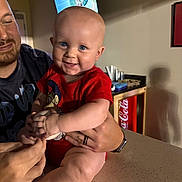 Memphis joined the competition — help win amazing prizes! baby, child, infant, smiling, holding, baseball, person, adult, indoor, counter, television, fridge, coca_cola, red_clothing, sock, hand, face, happy, casual, home