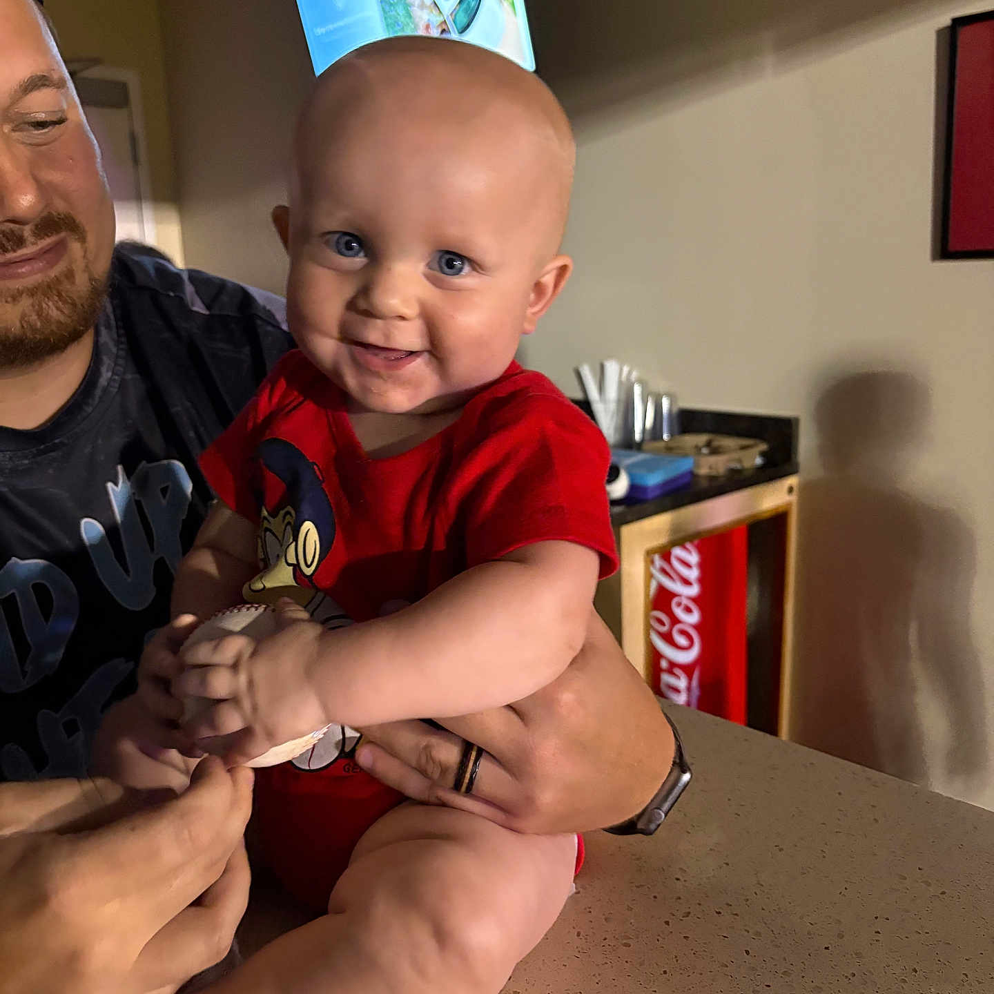 Memphis joined the competition — help win amazing prizes! adult, baby, baseball, casual, child, coca_cola, counter, face, fridge, hand, happy, holding, home, indoor, infant, person, red_clothing, smiling, sock, television