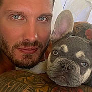 Mik is registered to the contest to win money with this photo: animal, bed, blue_eyes, closeup, companion, cute, dog, expression, face, french_bulldog, human, indoor, looking_at_camera, man, pet, portrait, resting, skin, tattoos, white_bedding