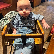 Rocky is registered to the contest to win money with this photo: baby, child, high_chair, restaurant, wooden_furniture, striped_shirt, jeans, curious_expression, indoor, flooring, seating, table, casual_clothing, infant, person, cute, small_hands, rolled_up_jeans, light_skin, wood