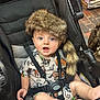 Rocky is registered to the contest to win money with this photo: baby, child, stroller, fur_hat, blue_eyes, outdoor, cute, infant, clothing, foot, expression, seatbelt, animal_print, hat, portrait, baby_clothes, playful, face, sitting, comfort