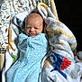 J.j. is registered to the contest to win money with this photo: baby, infant, blanket, blue_sleeper, smile, face, head, dinosaur_pattern, fabric, soft_texture, newborn, lying_down, cozy, child, cute, wrapped, colorful, animal_print, bed, comfort
