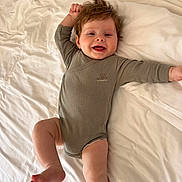 Gustave a rejoint le concours — aidez-le/la à gagner de superbes lots ! baby, infant, smiling, bed, bedding, onesie, hair, chubby_cheeks, face, portrait, lying_down, pillow, blanket, cozy, happy, skin, bare_foot, leg, bedroom, cute