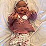 baby, child, infant, pink_clothing, headband, bow, patterned_pants, lying_down, bed, blanket, smiling, happy, cute, small_hands, footwear, indoors, portrait, young_child, soft_fabric, casual