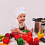 baby, child, infant, chef_hat, cooking, vegetables, bell_pepper, tomato, pot, utensils, spatula, ladle, smile, studio, white_background, playful, sitting, hands, food, portrait