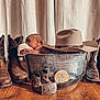 baby, newborn, metal_tub, cowboy_boots, cowboy_hat, wooden_floor, curtains, milestone, one_month, belt, wooden_plaque, infant, portrait, indoors, rustic, decor, flooring, clothing, hat, footwear