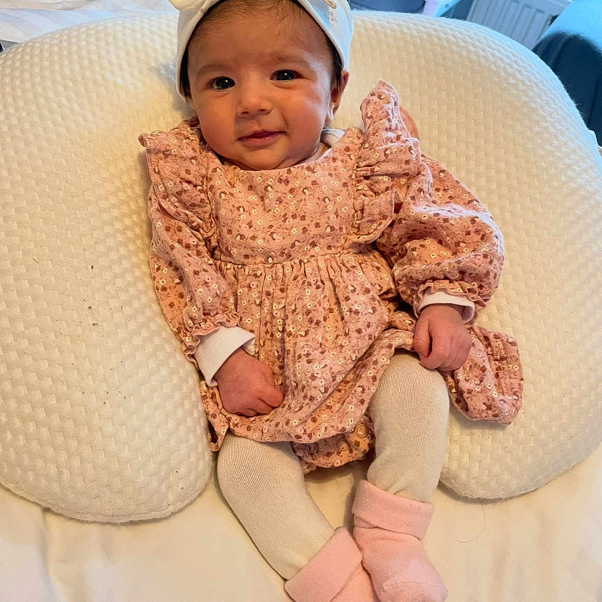 Ayra is registered to the contest to win money with this photo: baby, bed, blanket, child, comfort, cushion, cute, face, hands, headband, indoor, infant, legs, pink_dress, portrait, rest, smile, socks, soft, tights