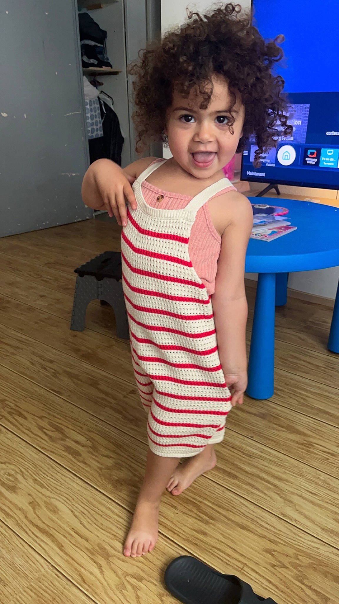 Alya a rejoint le concours — aidez-le/la à gagner de superbes lots ! baby_toddler_clothing, child, floor, flooring, fun, happy, hardwood, human_leg, joint, leg, person, skin, sleeve, smile, standing, t_shirt, table, thigh, thumb, toddler