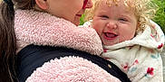 Hallie is registered to the contest to win money with this photo: baby, woman, child, curly_hair, pink_jacket, fleece, outdoor, greenery, smiling, happy, face, glasses, long_hair, hugging, nature, portrait, holding, person, warm_clothing, closeup