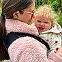 baby, woman, child, curly_hair, pink_jacket, fleece, outdoor, greenery, smiling, happy, face, glasses, long_hair, hugging, nature, portrait, holding, person, warm_clothing, closeup