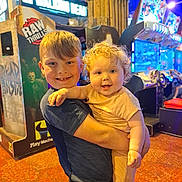 Hallie is registered to the contest to win money with this photo: arcade, arcade_machine, baby, boy, candid, child, clothing, colorful_lights, curly_hair, family, fun, happy, holding, indoor, infant, playing, portrait, short_hair, smiling, toddler