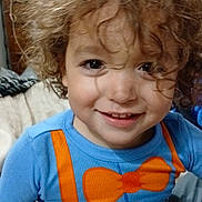 Lalo joined the competition — help win amazing prizes! child, toddler, curly_hair, smiling, blue_shirt, orange_bow_tie, orange_suspender, bed, blanket, indoor, portrait, happy, cute, person, face, young_child, casual_clothing, closeup, playful, cozy