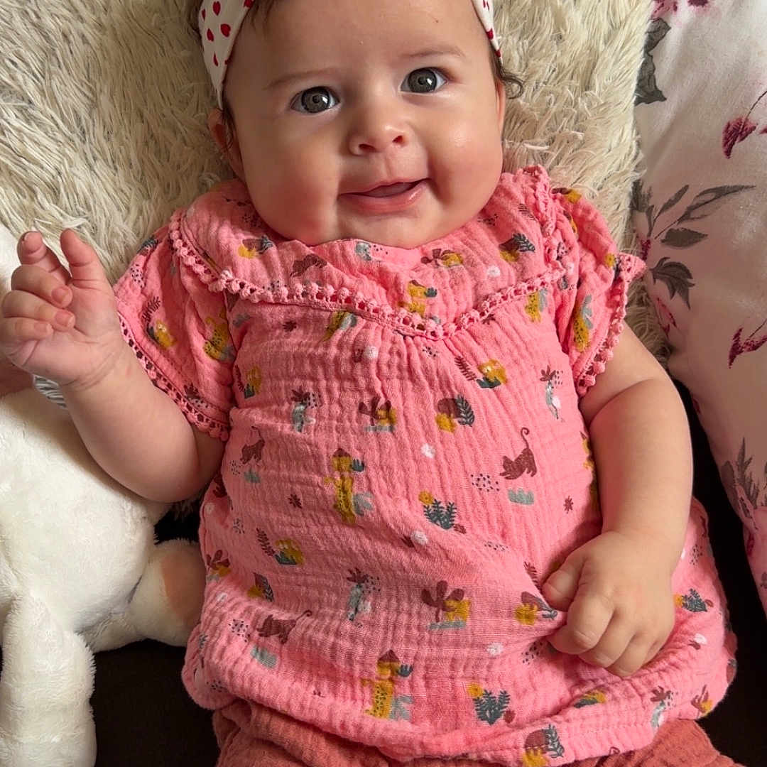 Avélina a rejoint le concours — aidez-le/la à gagner de superbes lots ! baby, child, cozy, cushion, cute, fabric, face, hand, happy, headband, indoor, infant, pillow, pink_clothing, plush_toy, portrait, seated, shorts, smiling, soft_texture