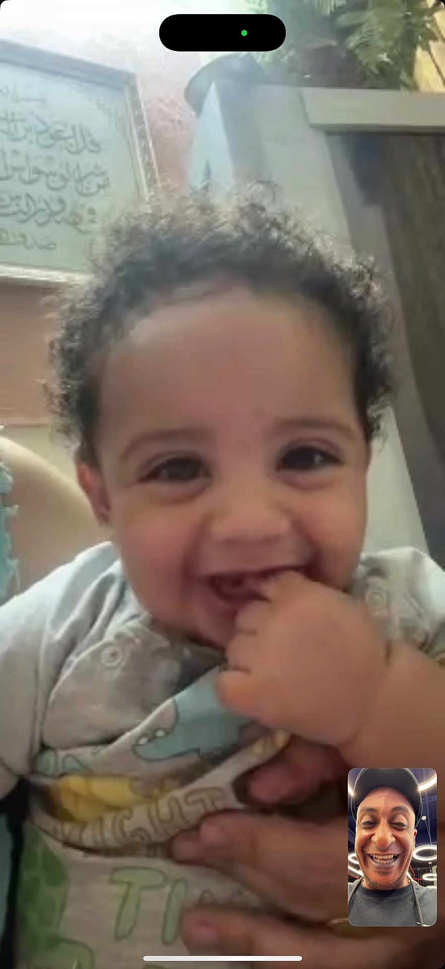 Elyas a rejoint le concours — aidez-le/la à gagner de superbes lots ! baby, child, smiling, face, curly_hair, hand, person, video_call, screen, adult, holding, indoor, clothing, happy, cute, portrait, digital_device, technology, communication, interaction