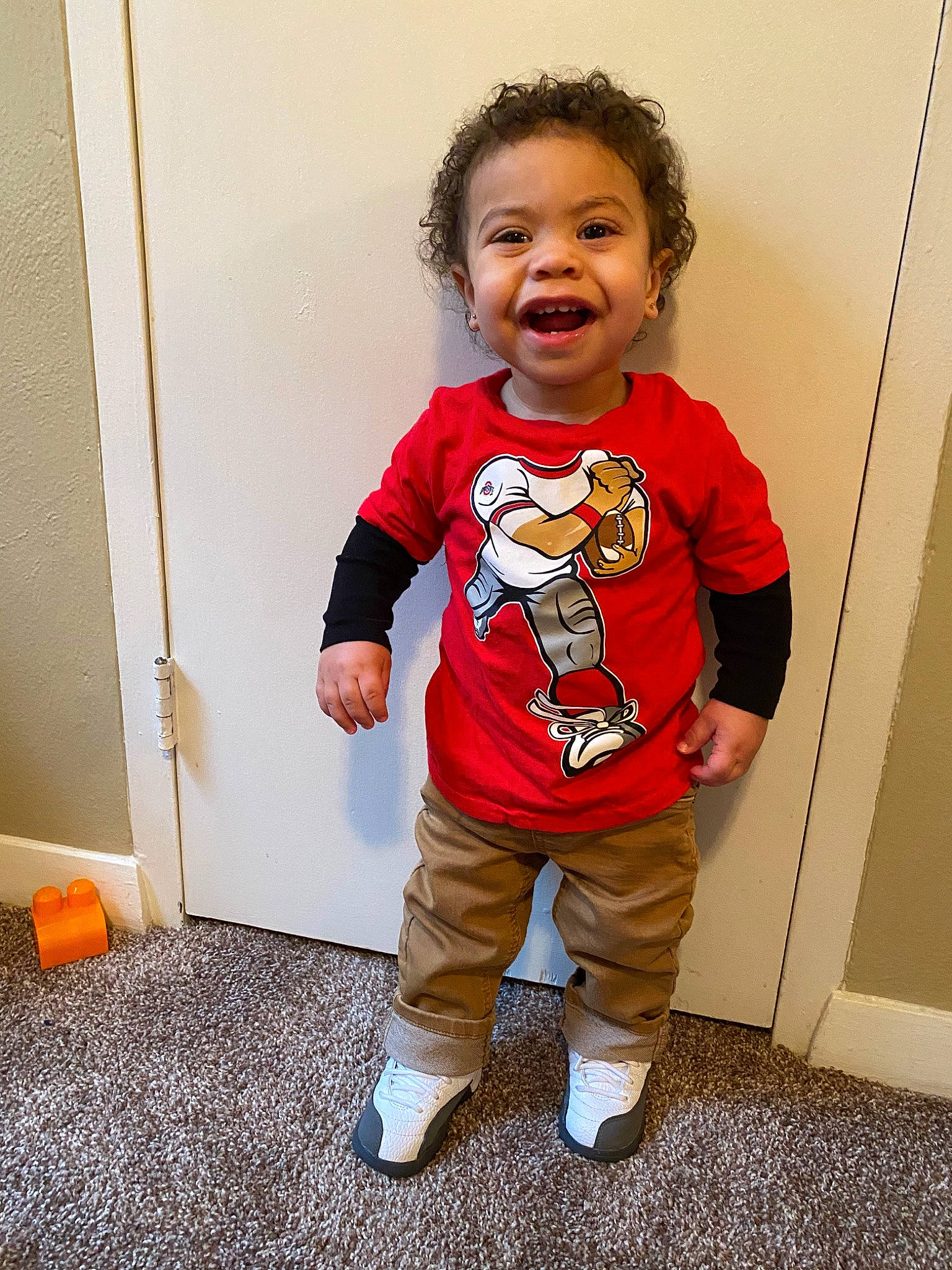 Jacob is registered to the contest to win money with this photo: baby, cheek, child, costume, face, fictional_character, outerwear, pajamas, person, play, red, sleeve, smile, standing, t_shirt, toddler