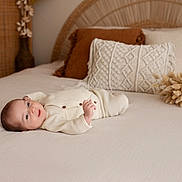 Valentin participe au concours pour gagner de l'argent avec cette photo : baby, infant, bed, pillow, blanket, soft_texture, cozy, indoor, resting, face, clothing, neutral_colors, decor, wooden, woven, calm, cute, relaxation, portrait, newborn