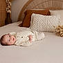 baby, infant, bed, pillow, blanket, soft_texture, cozy, indoor, resting, face, clothing, neutral_colors, decor, wooden, woven, calm, cute, relaxation, portrait, newborn