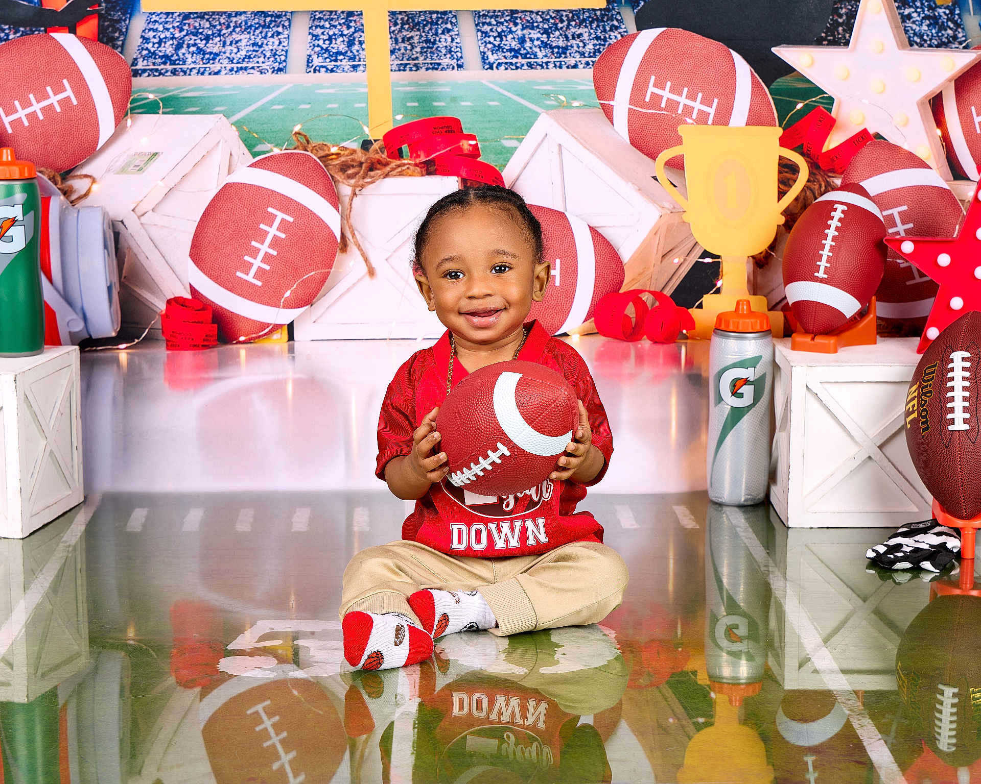 Christian joined the competition — help win amazing prizes! toddler, child, football, sports, toy, red_shirt, beige_pants, socks, smile, indoor, props, trophy, water_bottle, background, stadium, field, decorations, playful, reflection, photography