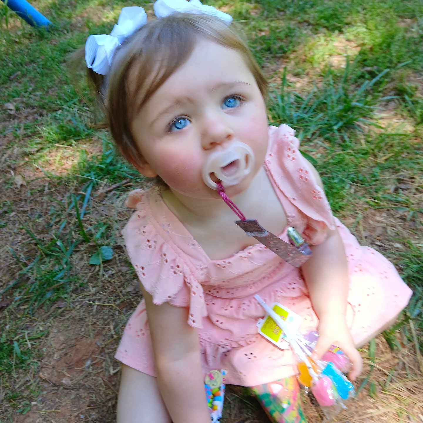 Lexee joined the competition — help win amazing prizes! baby, blue_eyes, bows, candy, casual, child, colorful, cute, face, grass, nature, outdoor, pacifier, person, pink_dress, playful, sitting, toddler, toy, young