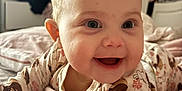 Nola joined the competition — help win amazing prizes! baby, smiling, infant, bed, blanket, onesie, animal_print, face, happy, cute, child, indoors, portrait, young_child, bedroom, soft_lighting, skin, person, cozy, sleepwear