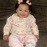baby, child, girl, smile, pink_bows, curly_hair, pajamas, animal_prints, socks, couch, brown_couch, indoors, happy, seated, comfortable, cute, portrait, infant, cozy, home