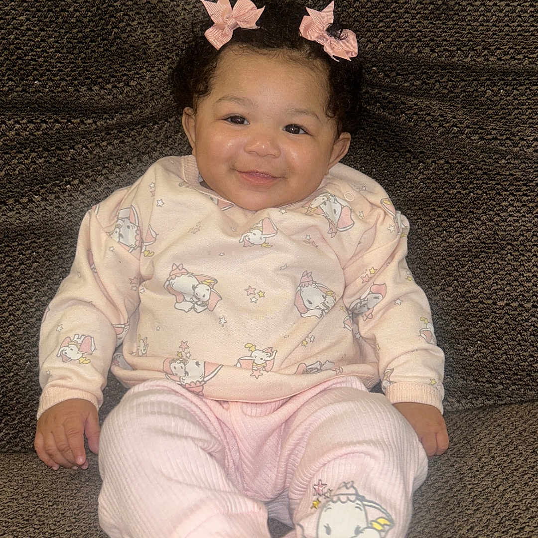 Miyori joined the competition — help win amazing prizes! baby, child, girl, smile, pink_bows, curly_hair, pajamas, animal_prints, socks, couch, brown_couch, indoors, happy, seated, comfortable, cute, portrait, infant, cozy, home
