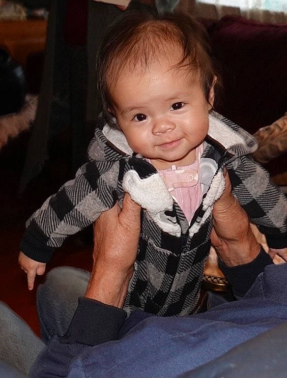 Maddy is registered to the contest to win money with this photo: baby, baby_toddler_clothing, bow_tie, button, cheek, child, child_model, comfort, eye, finger, hand, joy, lap, overall, person, pleased, sitting, sock, thumb, toddler