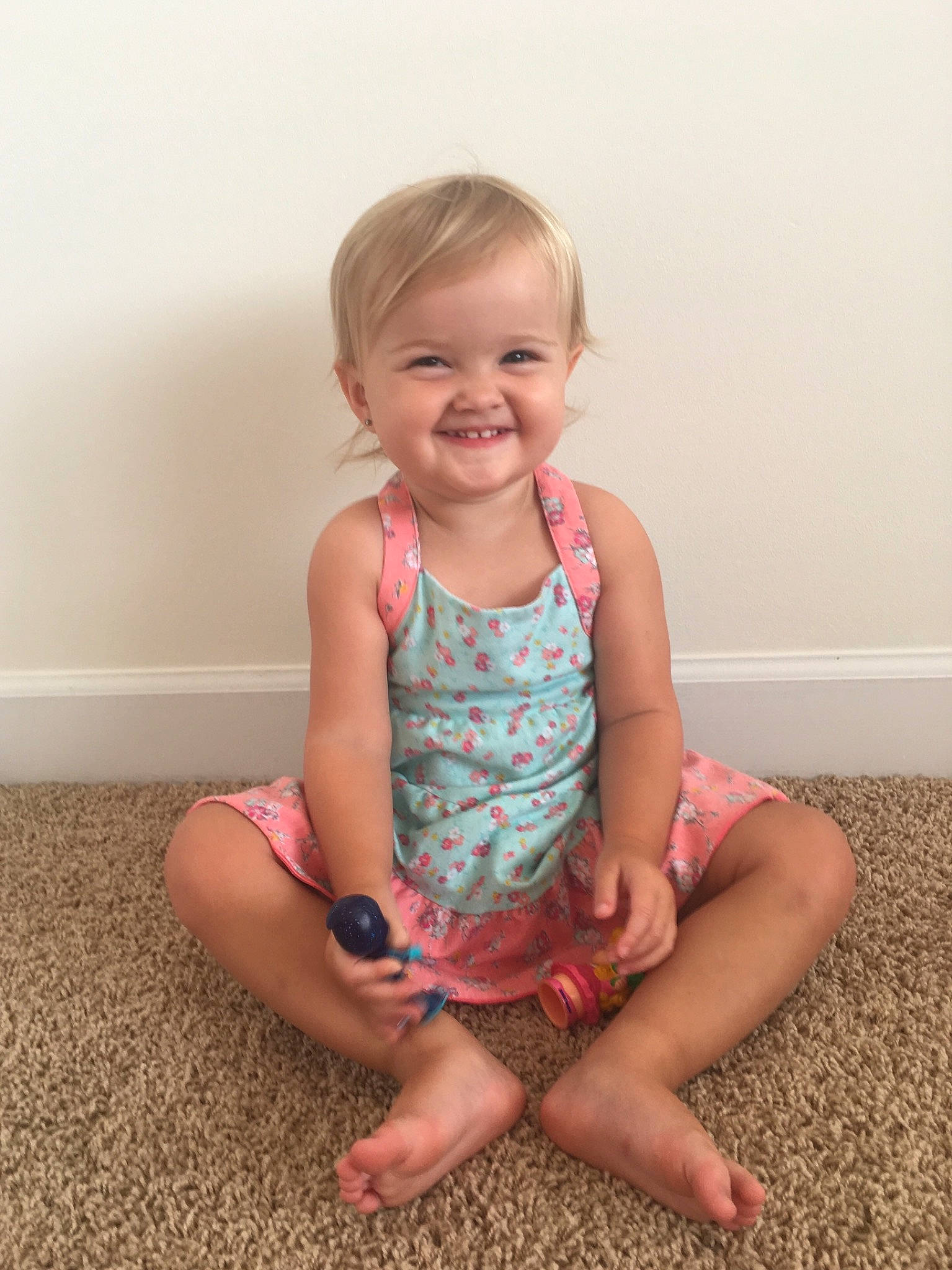 Ailie is registered to the contest to win money with this photo: arm, blond, child, dress, finger, floor, fun, human_leg, joint, joy, knee, leg, pattern, person, pink, play, sitting, skin, smile, standing