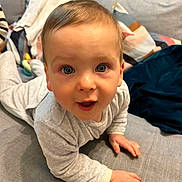 Albin participe au concours pour gagner de l'argent avec cette photo : baby, child, crawling, blue_eyes, gray_couch, blanket, cushion, soft_toys, indoors, clothing, long_sleeve, person, face, hands, curious, expression, home, comfort, cute, closeup