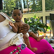 T Ruzin joined the competition — help win amazing prizes! baby, child, person, lap, diaper, drool, hair_buns, pink_pants, hand, plant, porch, outdoor, sunlight, pacifier, toy, furniture, greenery, skin, expression, clothing