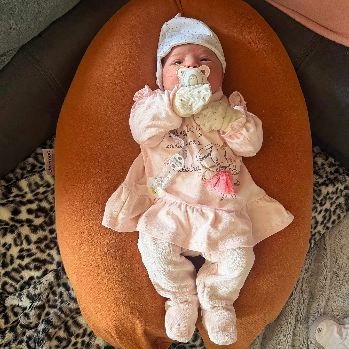 Lilou a rejoint le concours — aidez-le/la à gagner de superbes lots ! baby, infant, pacifier, pink_clothing, mittens, cushion, orange, blanket, leopard_print, soft_toys, cute, cozy, indoor, resting, headwear, footed_pants, small_person, newborn, sleepwear, comfort