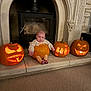 Autumn is registered to the contest to win money with this photo: baby, pumpkin, jack_o_lantern, carved_pumpkin, fireplace, halloween, costume, orange, candlelight, carpet, stone_hearth, baby_clothing, striped_leggings, cute, indoor, decoration, holiday, face, person, expression