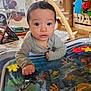 Adam is registered to the contest to win money with this photo: baby, child, infant, face, eyes, hand, toy, playmat, water_mat, colorful, floor, home_interior, furniture, drawer, wooden_floor, striped_clothing, curious, indoor, person, expression