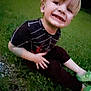 black_shirt, blonde_hair, casual_clothing, child, cute, dinosaur_shoes, evening, fun, grass, green_shoes, happy, nature, outdoor, person, playful, portrait, sitting, smiling, toothy_grin, young_child