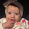 baby, infant, child, portrait, close_up, face, headband, bow, wide_eyed, smiling, hand, finger, mouth, eyes, pink, hearts, clothing, indoor, seated, photography