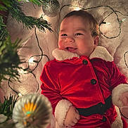 Noah Molina is registered to the contest to win money with this photo: baby, child, smiling, christmas, holiday, festive, red_clothing, santa_suit, blanket, lights, ornament, decoration, happy, face, infant, candid, cute, celebration, winter, indoors