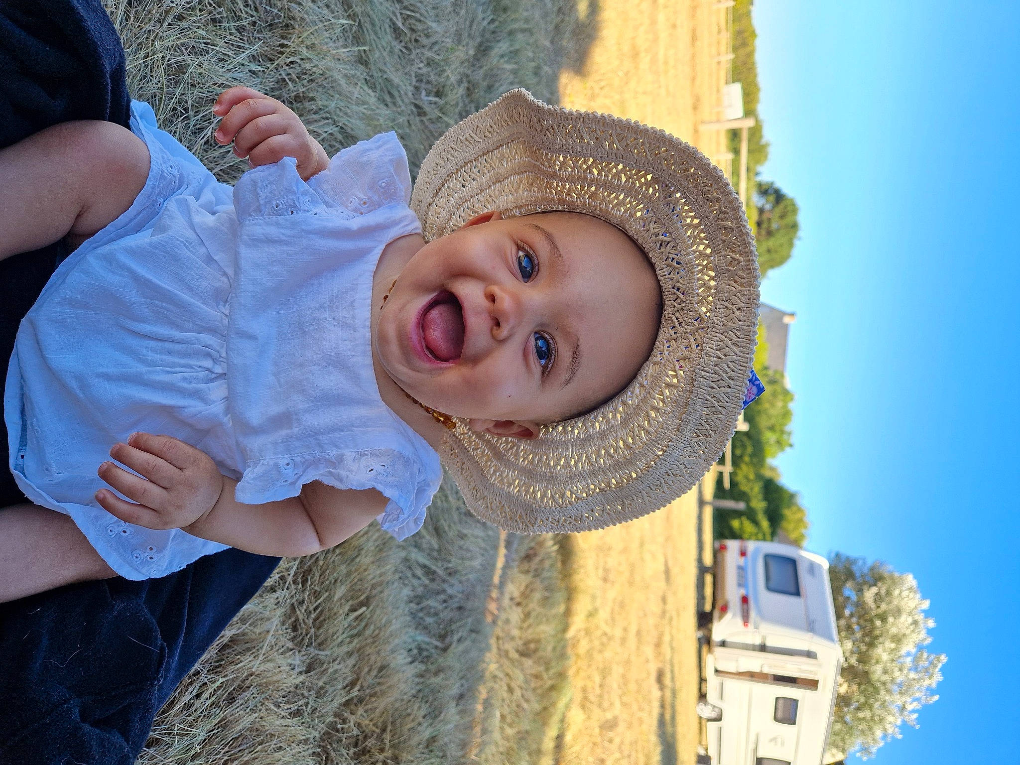Charlize participe au concours pour gagner de l'argent avec cette photo : blue, child, clothing, eye, fashion_accessory, fun, grass, happy, hat, head, headgear, landscape, leisure, people_in_nature, person, sky, smile, sun_hat, toddler, travel